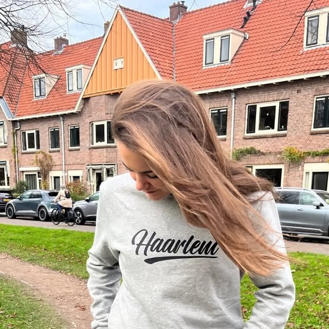 Meisje in een lichtgrijze HIZ-sweater met Haarlem erop.